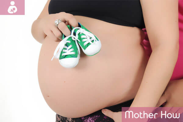 pregnant-lady-holding-baby-shoes